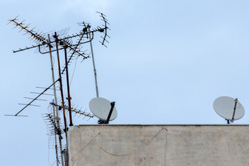 TV antennas and satellite dishes on the roof of a building in Athens, Greece. Cloudy day