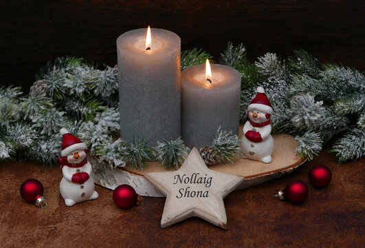 Christmas card Nollaig Shona: Santa Claus with candles, fir branches and Christmas balls on a star with the Irish text Nollaig Shona.