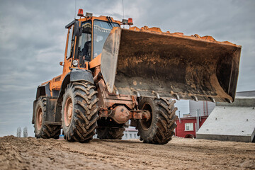 Heavy loader excavates soil on a construction site under overcast skies, showcasing the powerful...