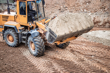 Heavy machinery moves sand at a construction site in the early morning light, preparing for a new...