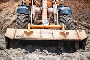 A powerful tractor digs into the earth, shaping the land at a construction site on a sunny...