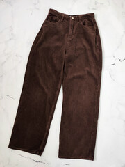 Brown corduroy pants front side flat lay at white marble background top view, clothes, fabric,...