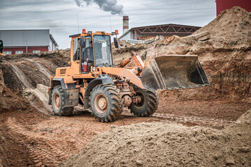 Obraz premium Heavy machinery works tirelessly on a construction site as dirt is moved and reshaped against an overcast sky in the background