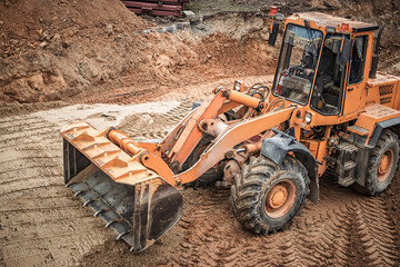 Heavy machinery working on a construction site during daylight hours, moving earth and material to create a solid foundation for new structures