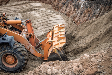 Excavator digging into soft earth at a construction site, preparing for a foundation, under...