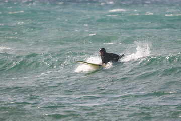 surfer in a wetsuit on a board glides through the waves in a strong wind