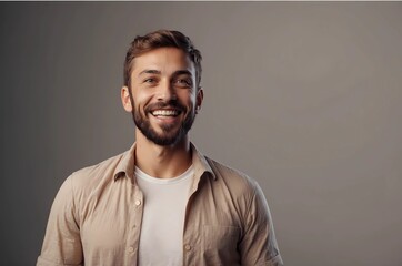 Obraz premium Portrait of smiling young bearded handsome man looking to the side with his eyes and open mouth wearing white t-shirt and beige shirt isolated on grey wall background with copy space. (1)