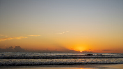 A beach view at sunset with clouds creating a dramatic yet calm atmosphere, evoking the beauty and...