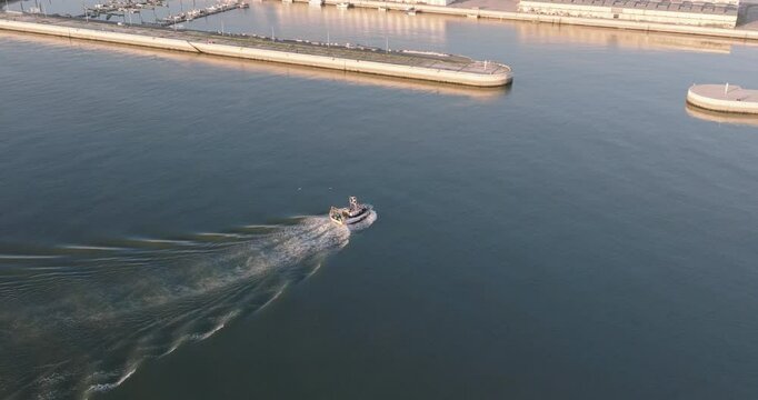 Aerial drone shot of fishing boat coming into port at the Doca de Pedrou&ccedil;os marina in Belem, Lisbon, Portugal, Europe. Golden hour before sunset. Shot in ProRes 422 HQ