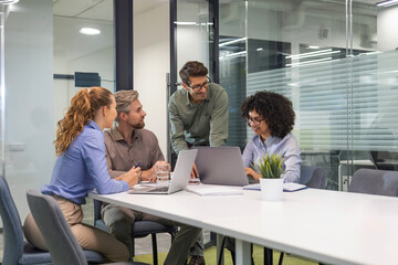 Group of young modern people in formalwear using modern technologies while working in the creative office