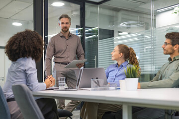 Obraz premium Business people discussing work together using a tablet and laptop taking notes in a modern office