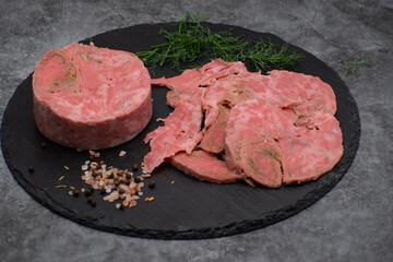 Vegan ham made of wheat gluten, shaped and cooked in a ham press. Sliced, slate board.