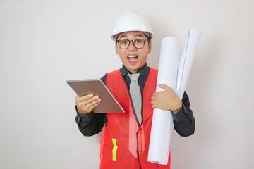 Smiling young asian civil engineer helmet hard hat standing showing thumbs up on isolated white...