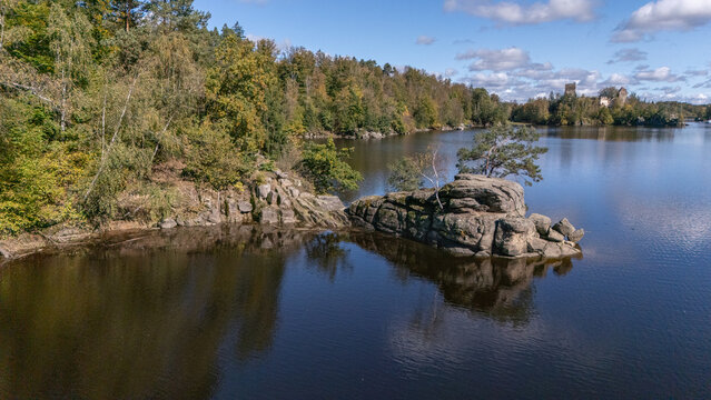 Drohnenaufnahme vom Stausee Ottenstein, B&auml;ume wachsen am Uferrand auf Felsen, im Hintergrund sieht man eine Ruine