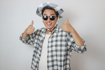 Overjoyed asian man wearing sunglasses dancing, makes movements to music, smiles positively, being in high spirit. isolated on blue background. holiday and vacation concept.