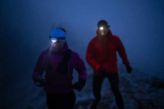 Night trail runner of men and women running on the mountain.at night milky way