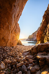 Hidden cove and beach with an old hilltop village. The sunrise is reflected in the water. A beautiful landscape shot framed by cliffs and the Adriatic sea from Vrbnik, Krk, Croatia