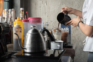 A female barista in a cafe is preparing drinks according to customer orders
