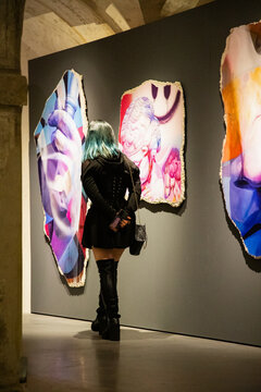 Elegant woman viewing artwork in a gallery, immersed in the beauty of modern art exhibition.