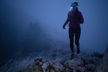 Exercising outdoors is healthy for active lifestyle runners. Autumn trail run woman running in nature from behind in dark forest. Outdoor jog.