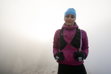 woman hiker or triathlon trail runner portrait on a trail in the mountains with fog at sunset
