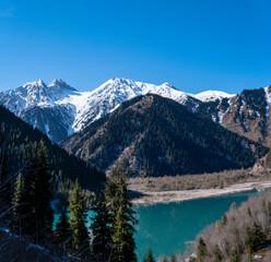 Panorama of Lake Issyk in the mountains in autumn with emerald water and reflection of the mountains. A beautiful high-altitude lake near Almaty, Kazakhstan. A popular tourist destination.