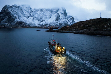 A fishing boat skillfully navigating through snowy waters surrounded by majestic mountains,