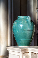 Teal Greek Vase Against a White Columned Wall.