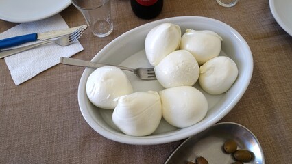 A tray full of fresh mozzarella just served at the table.