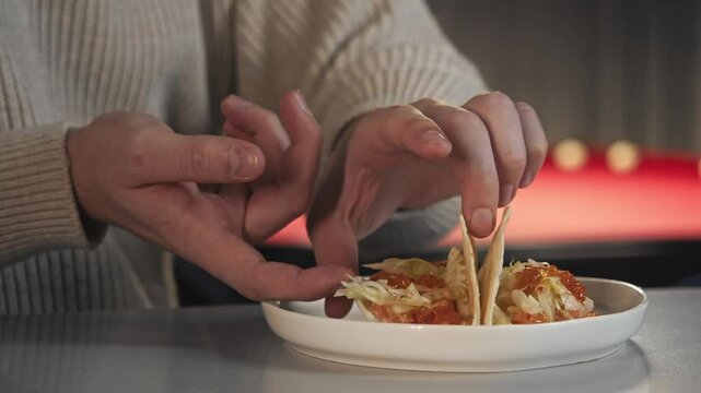 Client in night cafe is trying an unusual taco recipe with seafood and a tortilla. In background see pool table. Close up.