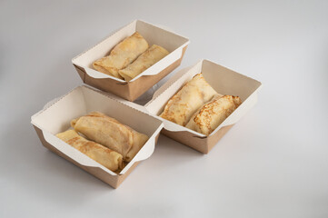 Three takeout boxes filled with neatly folded crepes, ready for delivery or takeaway, photographed against a plain background.