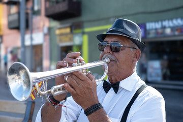 Portrait of jazz artist outdoors concert. Elderly man with black hat and sunglasses playing a...