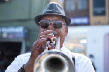 Jazz artist outdoors concert. A mature man with black hat playing a trumpet in the street. Male...