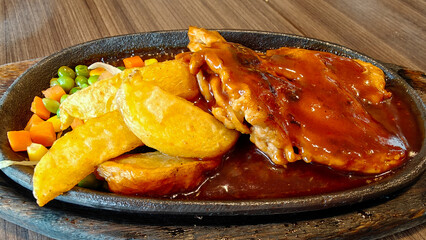 Crispy Chicken Steak with french fries and vegetables on black wooden plate