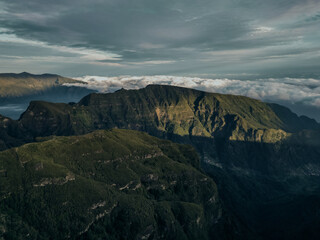 A stunning view of the first rays of the sun bathing the rugged peaks of the madeira mountains in a golden glow, highlighting the spectacular natural topography