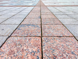 A series of granite paving stones forms a distinct pathway through a public square, showcasing...