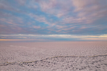 Aerial view on an ice on the Onega lake covered with ice in Republiс of Karelia in winter in a sunset