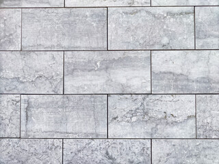Fototapeta premium Textured gray stone wall featuring rectangular tiles arranged in a neat pattern, suitable for modern interiors or exteriors
