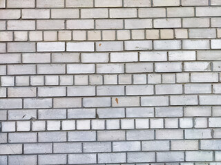 Gray brick wall with varying textures and patterns in natural light