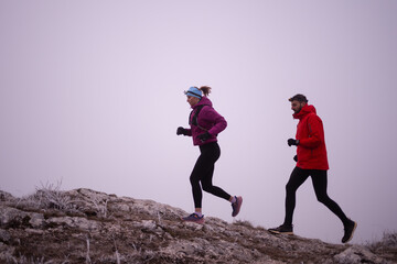 Athlete couple trail running on the mountain top in the early morning. Sky running concept