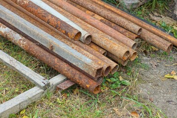 part of water drainage supply  round industrial iron rusty brown long heavy pipes lie on ground in...