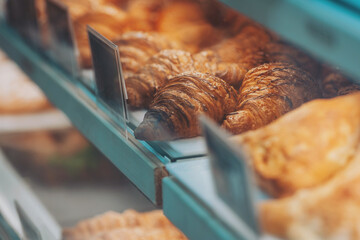 Interior details at the bakery and coffee shop. Bistro showcase with shelves of freshly croissants and bread in assortment. Zero waste shop or sustainable local small businesses at food service. 