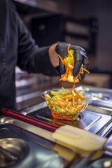 Chef in the kitchen making delicious looking salad.