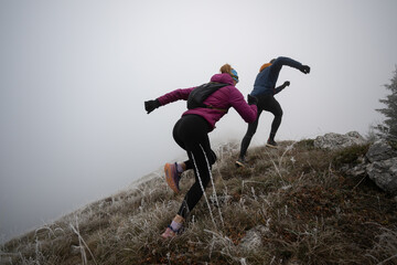 trail running couple man and woman running on a mountain path