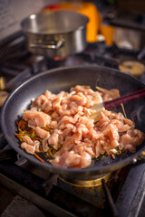 Chef frying cut vegetables and chicken in pan in restaurant kitchen.