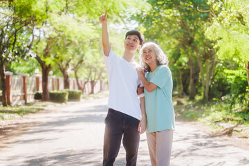 Young son and his mature mom asian people share loving hug in beautiful park, surrounded by nature. Their happiness radiates as they bond outdoors, celebrating family love and togetherness.