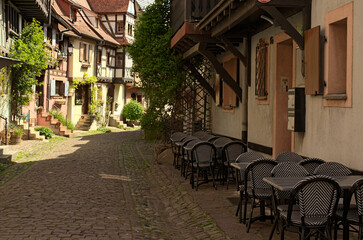 Charming cityscape view of narrow medieval cobblestone street between colorful stone houses in Eguisheim. Traditional architecture in Alsace in northeastern France. Travel and tourism concept