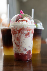 Strawberry yogurt smoothie in take away glass on wood table at cafe