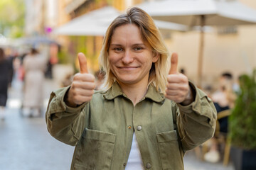 Like. Happy young woman looking approvingly at camera showing double thumbs up, like sign positive something good positive feedback. Lovely girl stands on urban city street. Town lifestyles outdoor.