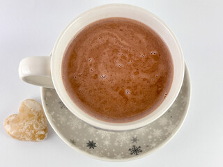 cup of hot chocolate with milk and heart-shaped cookie on a white isolated background